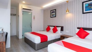 A hotel room with two beds, each with red and white bedding, a small bedside table, a wall-mounted light, and a door leading to a bathroom. - Big Big Hotel (Johor Bahru)