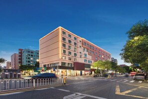 A multi-story hotel with a modern design, located at a city intersection. - Shenzhen Asia Yue Hotel(Bao'an Central Stadium Fanshen Subway Station Store) (Shenzhen)