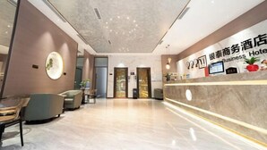 Un moderno vestíbulo de hotel con una recepción, zona de estar y un espejo grande.