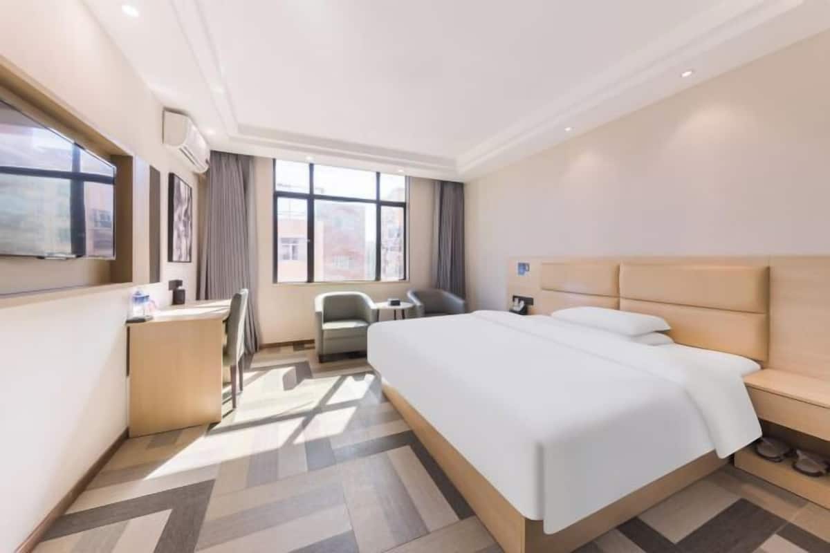 Una habitación de hotel con una cama grande, un escritorio, una silla y una ventana.