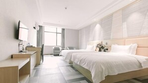 Una habitación de hotel con una cama grande, un escritorio, una silla y un televisor.