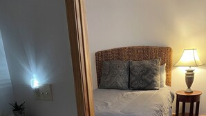 A bedroom with a wooden floor, a bed with patterned pillows, a bedside lamp, and a nightstand. - Unique apartment in historic downtown (Vandalia)