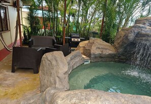 A pool area with a waterfall, surrounded by rocks and greenery. - Altos del Arenal Villas<br>: Private pool, air conditioning, volcano view (Monterrey)