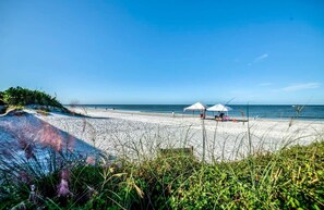 Une plage avec des parasols blancs et une rive sablonneuse.