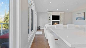 A modern kitchen with white cabinetry, a large island, and a fireplace. - Modern Waterfront Home on Georgian Bay w/ Hot Tub! (Victoria Harbour)