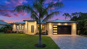 Une maison moderne à deux étages, dotée d’une pelouse bien entretenue, d’une allée et d’un garage.