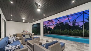 Un espace de vie extérieur moderne, doté d'une piscine, de meubles en osier et offrant une vue sur le ciel au crépuscule.
