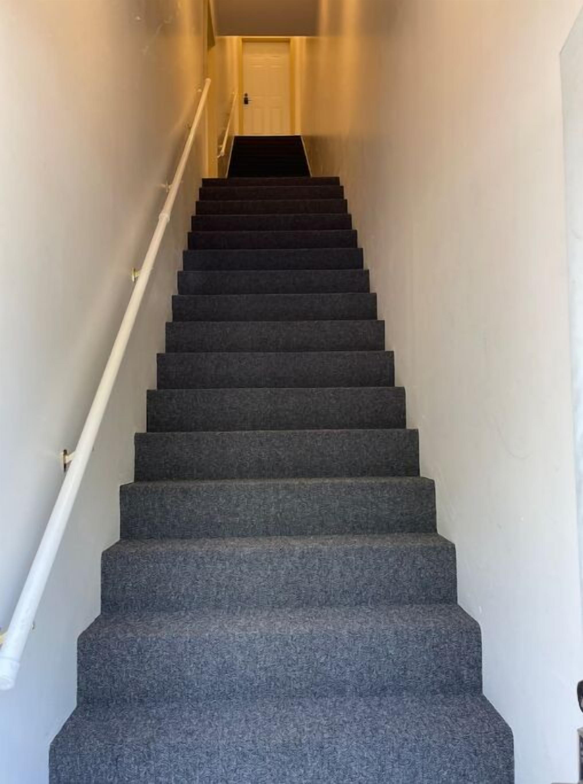 Una escalera con peldaños alfombrados que conduce a una puerta en la parte superior.