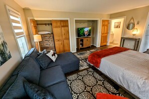 Une chambre d’hôtel comprenant un lit, un canapé, une télévision, une armoire et un miroir.