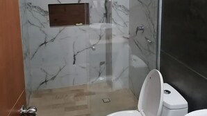 Un baño con ducha acristalada, inodoro y lavamanos.