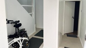 Un intérieur moderne avec un escalier, un vélo blanc et une porte donnant sur une autre pièce.