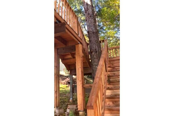 A wooden staircase leading up to a wooden deck with a railing. - The Tree House of Paradise (Salem)