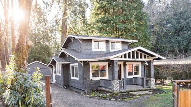 A two-story house with a porch and a stone foundation.