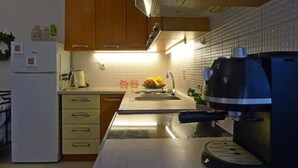 Ett kök med träskåp, en diskho i rostfritt stål, en kaffebryggare och ett kylskåp.