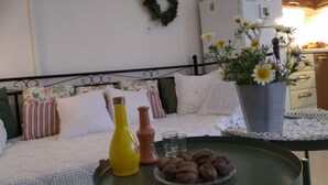 Ett mysigt rum med en säng, ett litet bord med snacks, en vas med blommor och ett kylskåp.