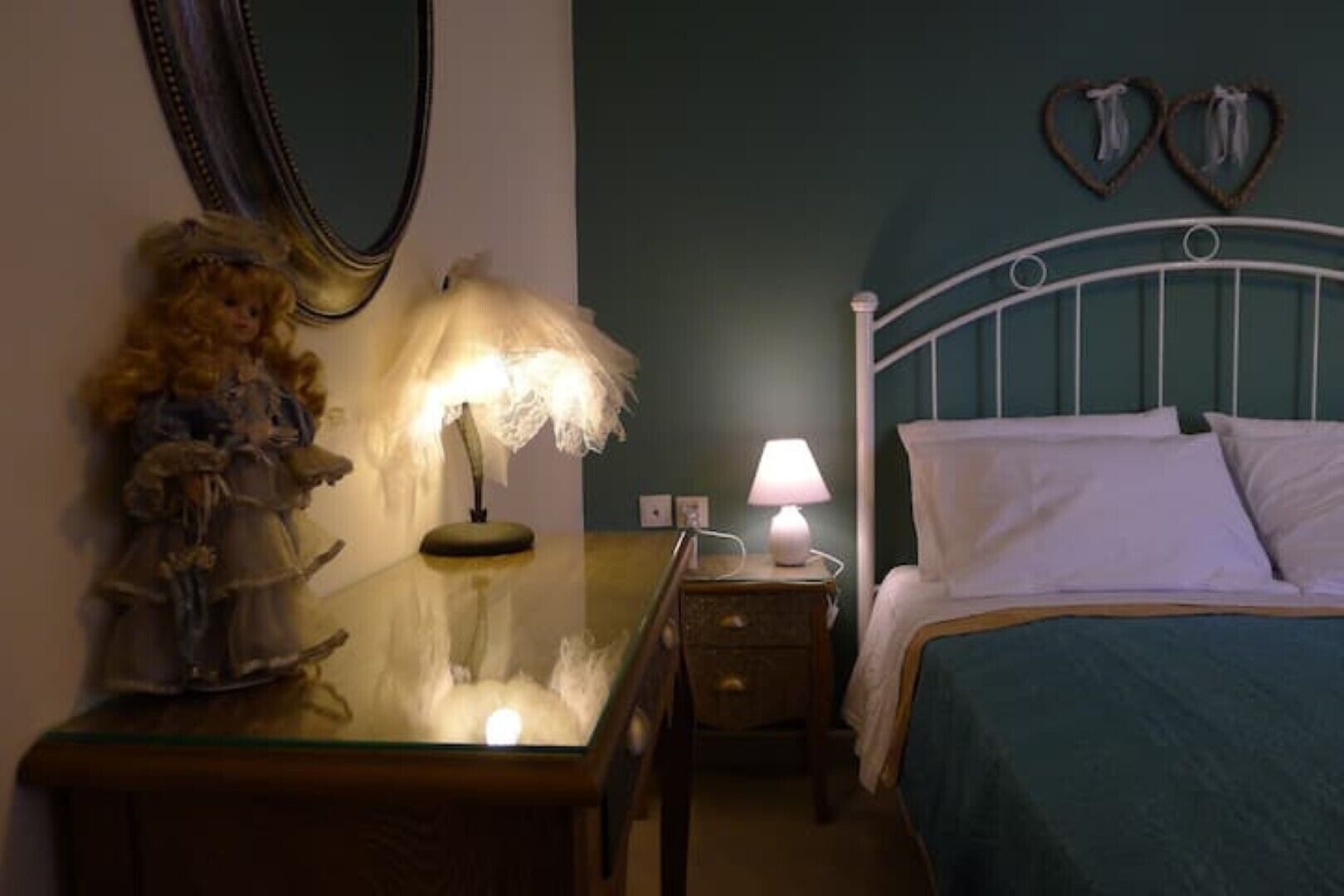 Un dormitorio con cama, dos mesitas de noche, lámpara, espejo y adornos.