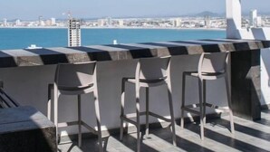 Un bar en la azotea con vistas a la ciudad y al mar.
