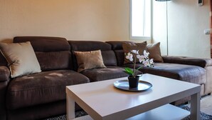 Un salon moderne avec un canapé en cuir marron, une table basse blanche et une orchidée en pot.