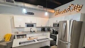 Een moderne keuken met witte kastjes, roestvrijstalen apparatuur en een centraal eiland met krukken.
