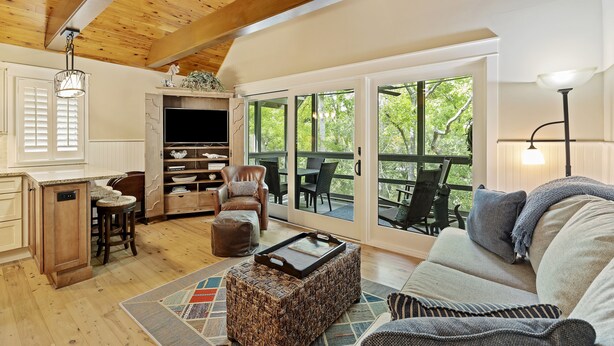 A spacious living area with a wooden ceiling, a large window, and a cozy seating arrangement.