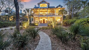 A two-story house with a front porch, a driveway, and a pathway leading to the entrance. - Stunning 7 BR Home on Eugenia, Private Pool, 100 yards to Beach! (Kiawah Island)
