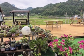 En terrasse med plantekasser, en gyngestol og udsigt over et grønt landskab.
