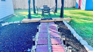 Een terras met een pergola, tuinmeubilair en een pad.
