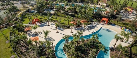 Un resort con una piscina grande, palmeras y vistas de la zona residencial circundante.