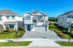 Stunning two-story home with a central entrance, flanked by windows, and a balcony above.