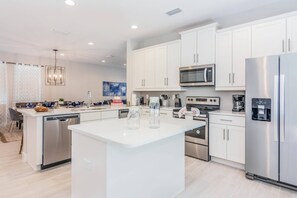 Enjoy cooking in this well-equipped kitchen with a central island, dishwasher, refrigerator, and microwave.