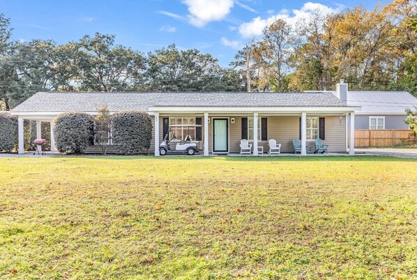 A single-story house with a covered porch, a lawn, and a wooden fence.