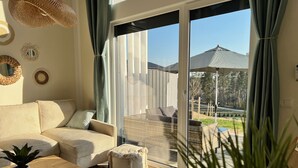 A living room with a sofa, coffee table, and a view of the outdoor patio area. - Casa Kashubia Sansibar - Premium vacation home by the lake - near the Baltic Sea (Brzezno Szlacheckie)