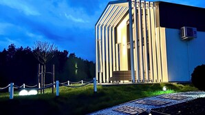 A modern building with a unique architectural design, featuring vertical lines and a slanted roof. - Casa Kashubia Sansibar - Premium vacation home by the lake - near the Baltic Sea (Brzezno Szlacheckie)