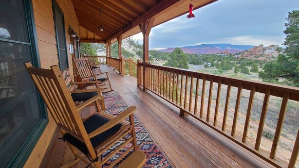 Une terrasse en bois avec des fauteuils à bascule et une vue sur un canyon.