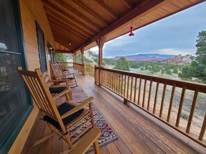 Um deck de madeira com cadeiras de balanço e vista para um cânion.