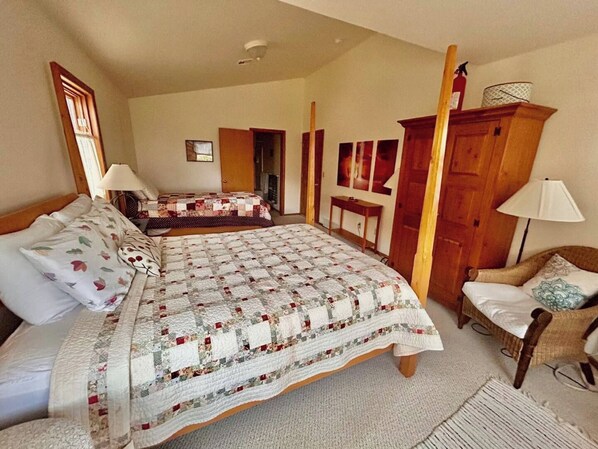 Quarto com uma cama grande, uma cama menor, uma cadeira e um guarda-roupa.