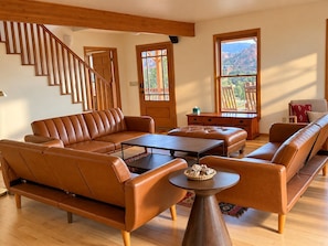 Ein modernes Wohnzimmer mit einem braunen Ledersofa, einem Couchtisch und einer Holztreppe.