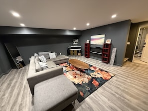 Ein modernes Wohnzimmer mit einem grauen Sofa, einem Couchtisch und einem großen Teppich mit Blumenmuster.