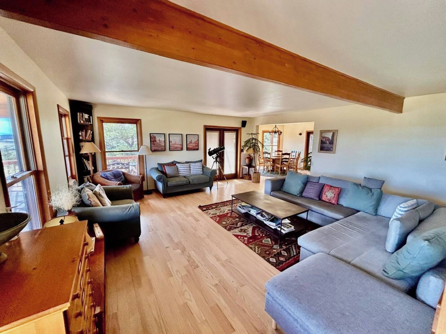 A spacious living room with a wooden ceiling, a large sofa, a coffee table, and a bookshelf.