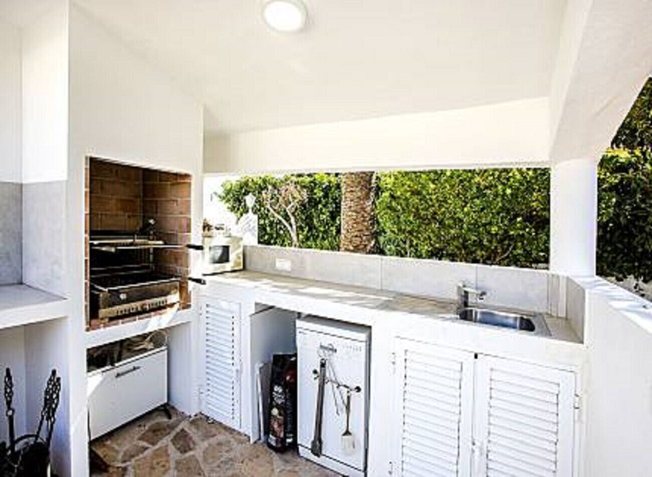 A compact outdoor kitchen with a built-in grill, a sink, and a small storage area.