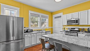 A modern kitchen with white cabinets, stainless steel appliances, and a marble countertop.