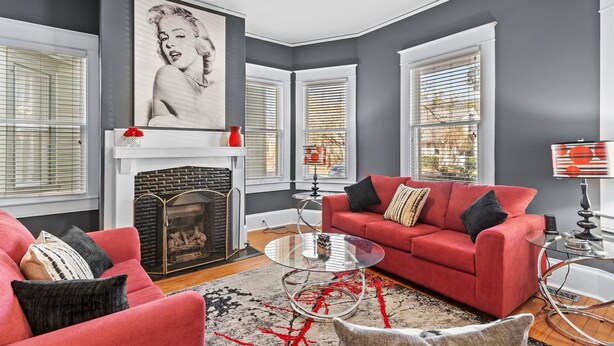 A living room with a fireplace, red sofa, and a glass coffee table.