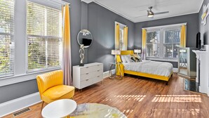 A bedroom with a bed, a chair, a dresser, and a mirror.