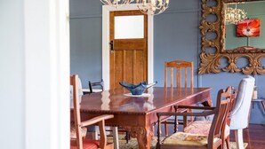 Un comedor con una mesa y sillas de madera, una araña y un espejo con marco decorativo.