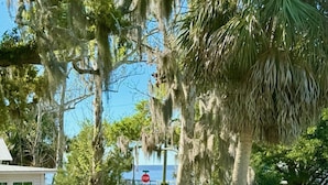 A residential area with a red car parked on the street, a white shed, and a stop sign. - Osprey Nest- Historic Cedar Key. Pet Friendly! (Cedar Key)