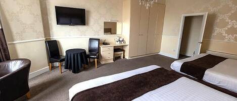 A hotel room with two beds, a desk with a chair, a television, and a wardrobe.