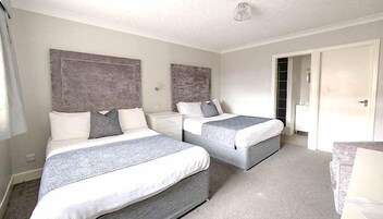 Een hotelkamer met twee bedden, een nachtkastje, een garderobe en een deur.
