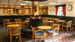 A restaurant with a black cushioned booth, wooden chairs, and tables.