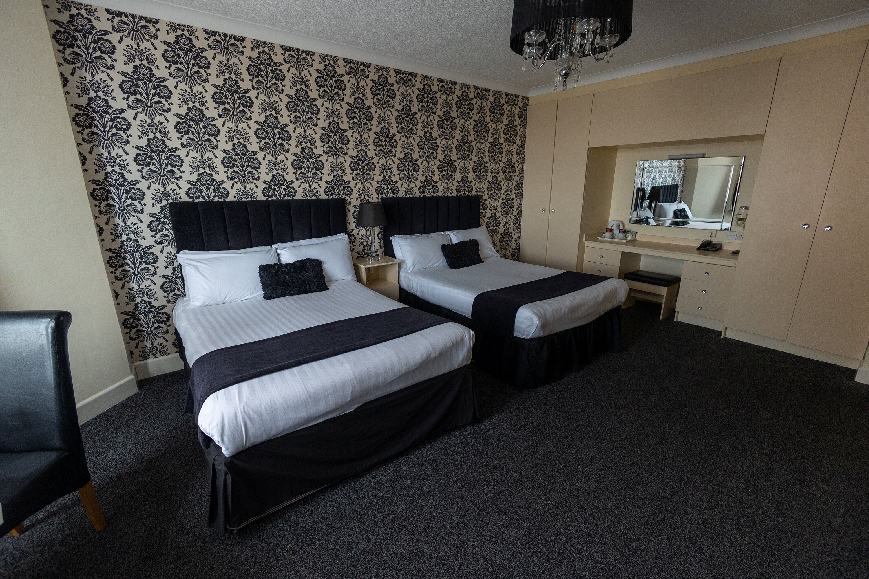 Une chambre d’hôtel avec deux lits, une commode, un miroir et une chaise.