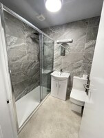 A modern bathroom with a glass shower enclosure, a white sink, and a toilet.